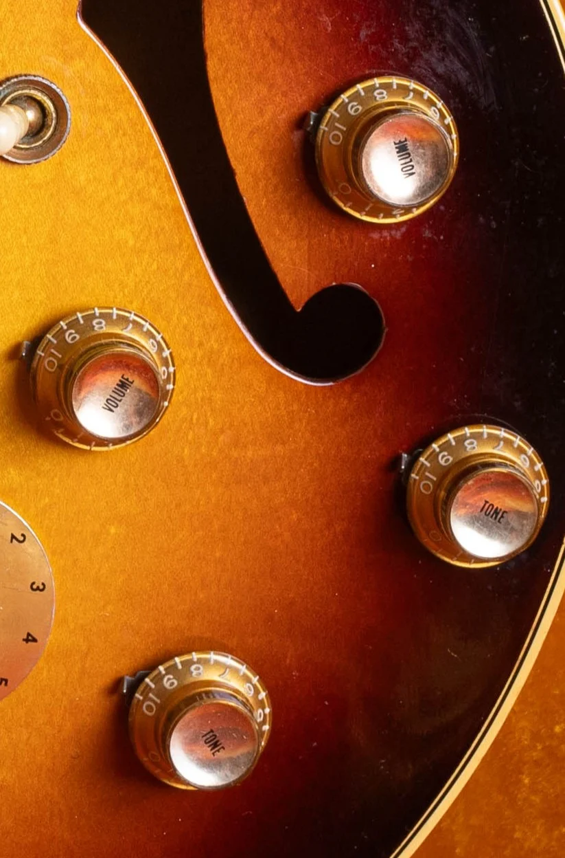 Four gold Gibson reflector knobs with metal volume and tone inserts on a sunburst hollowbody guitar