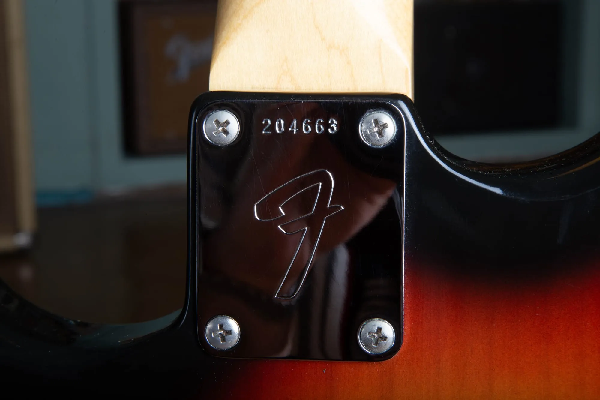 Chrome four-bolt F neck plate on the back of a 1967 Fender Stratocaster, stamped with serial number 204663 above the large Fender F logo.