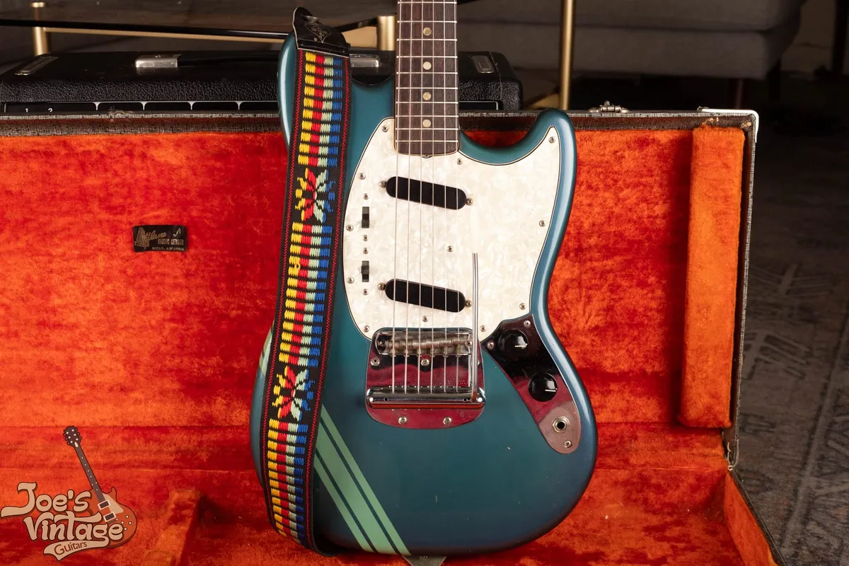Front of a 1971 Fender Competition Mustang in Competition Blue with seafoam racing stripes, a pearloid pickguard, and the Dynamic Vibrato, in its original orange-lined case. We buy vintage Fender Mustangs nationwide at Joe's Vintage Guitars.