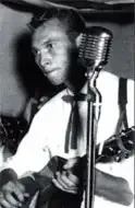Bob Denton singing and playing guitar at a microphone