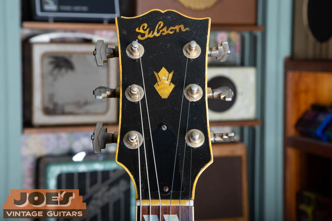 1946 Gibson headstock with a pearl script logo and crown inlay under ambered lacquer