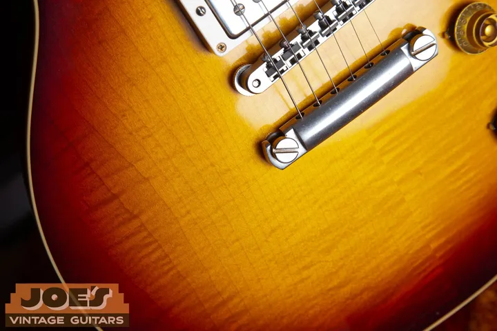 Close-up of a Gibson Les Paul cherry sunburst finish over figured maple beside the bridge and tailpiece