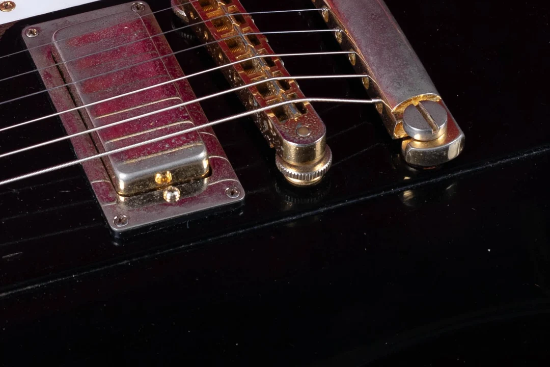 Gold Gibson Nashville Tune-O-Matic bridge on a black Firebird guitar