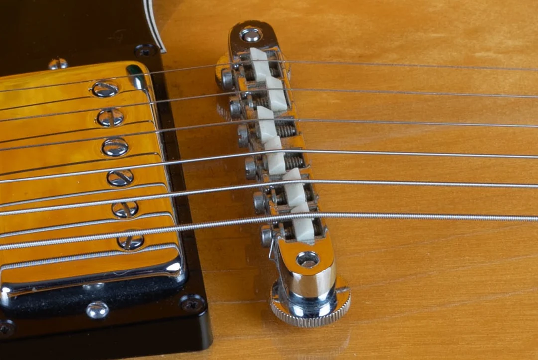 Top view of a wired Gibson ABR-1 bridge with a retaining wire across the saddle screws